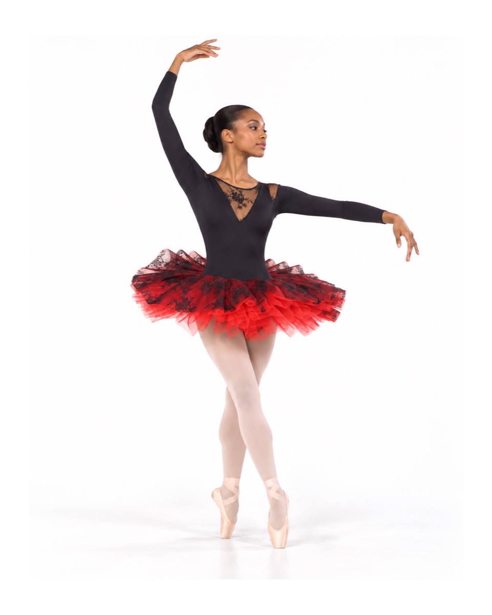 Bailarina de ballet con maillot negro y tutú rojo y negro de Isance, de puntillas con un brazo en alto
